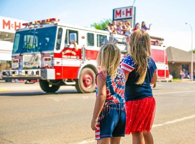 Kids watching a firetruck in a parade.